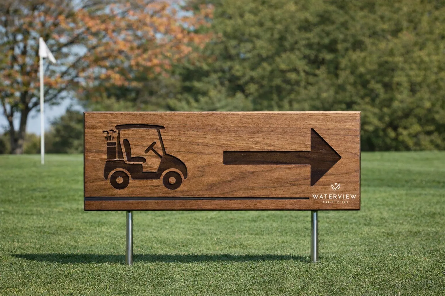 Walnut directional cart sign with engraved golf cart graphic and arrow for Waterview Golf Club, on steel legs on the fairway.