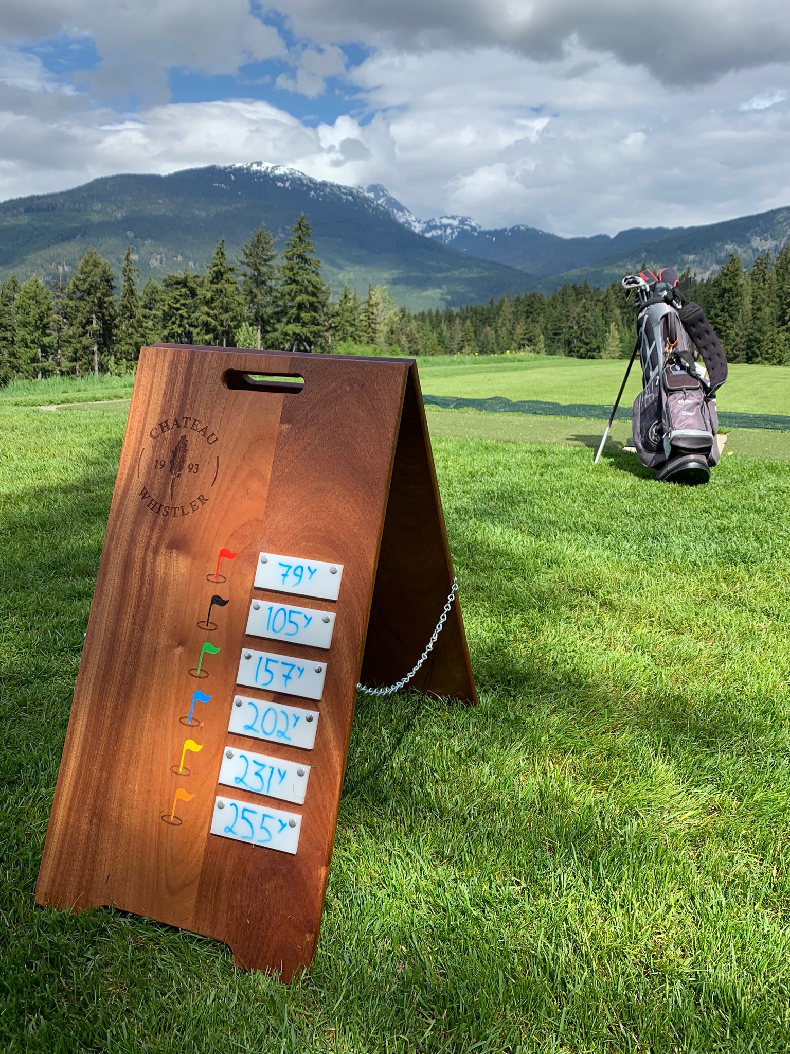 A-frame yardage marker on the fairway at Fairmont Chateau Whistler with mountain backdrop.
