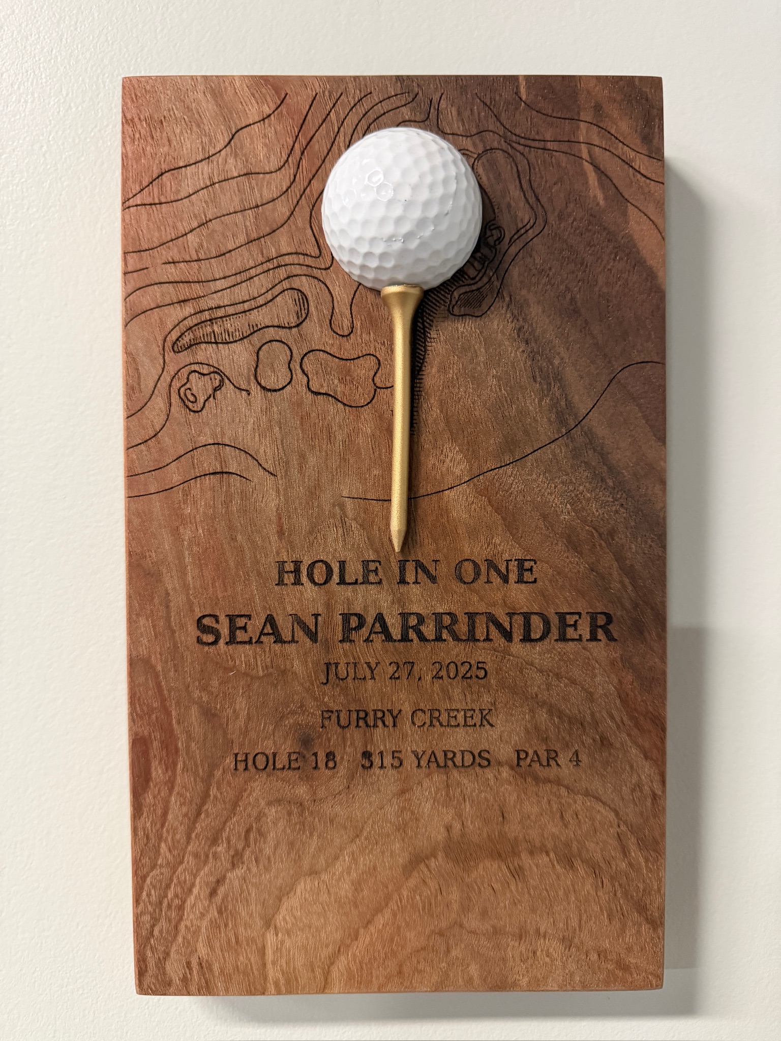 Walnut hole-in-one plaque for Sean Parrinder, Furry Creek, with engraved topographic contour lines, golf ball on gold tee.